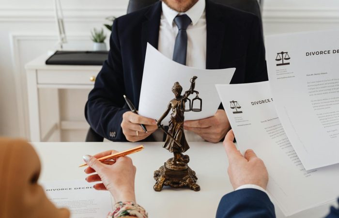 Legal professionals reviewing divorce documents in a law office with a Lady Justice statue.