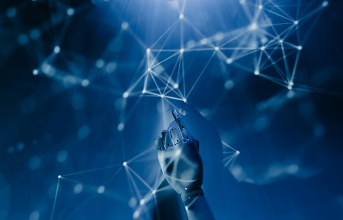 A robotic hand reaching into a digital network on a blue background, symbolizing AI technology.