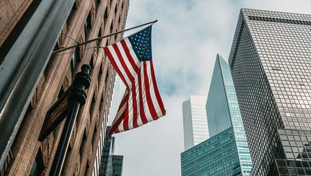 U.S. flag surrounded by modern office buildings in a major American city