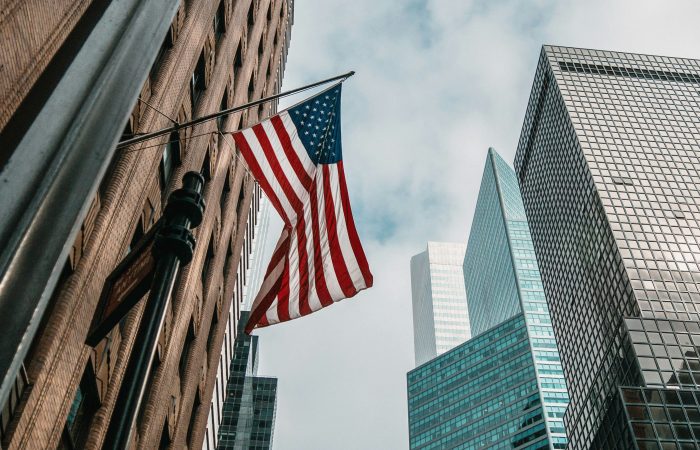 U.S. flag surrounded by modern office buildings in a major American city