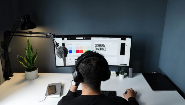 Graphic designer working on a computer at a desk with a color palette displayed on the monitor