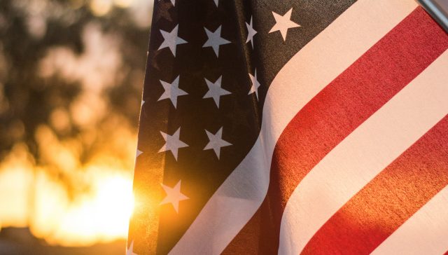 American flag waving against a sunset sky representing U.S. immigration opportunities