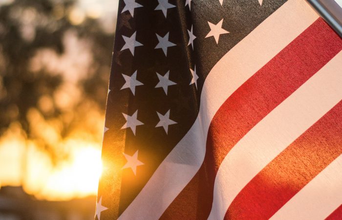 American flag waving against a sunset sky representing U.S. immigration opportunities