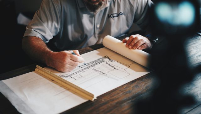 An architect reviewing architectural blueprints and drafting designs for a U.S. immigration petition.