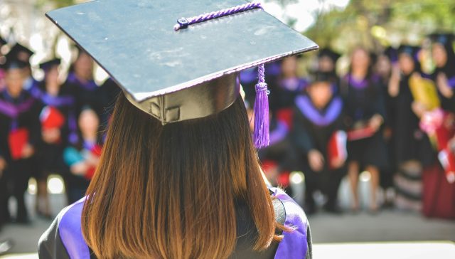 A student wearing a graduation cap and gown, representing advanced degrees and academic requirements for U.S. immigration.