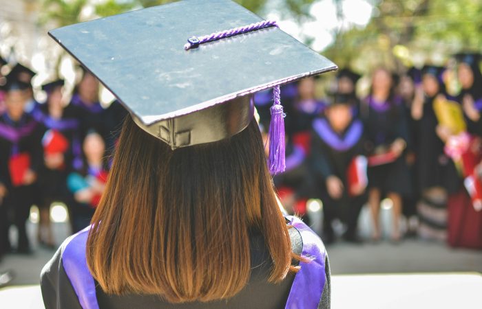 A student wearing a graduation cap and gown, representing advanced degrees and academic requirements for U.S. immigration.
