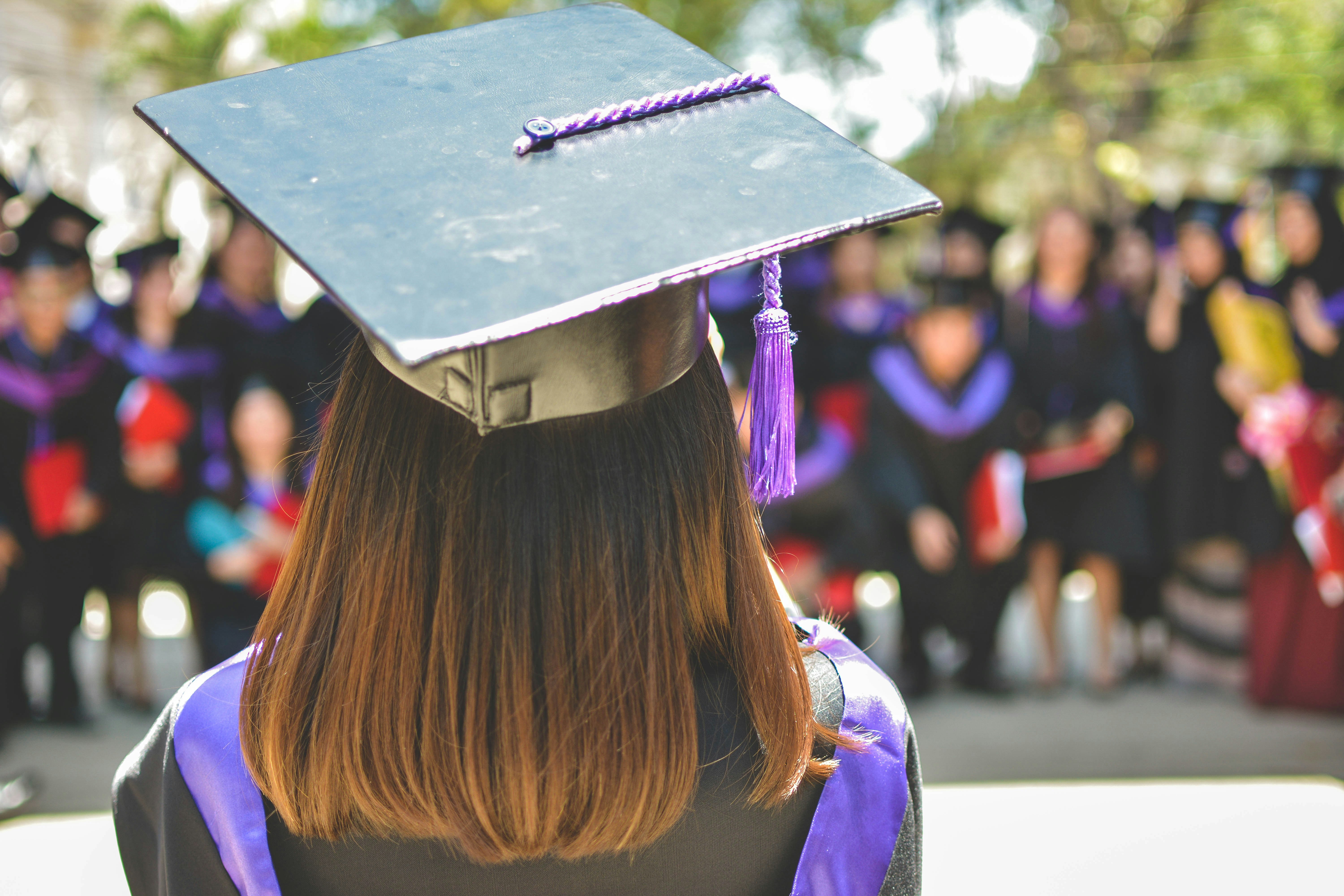 A student wearing a graduation cap and gown, representing advanced degrees and academic requirements for U.S. immigration.