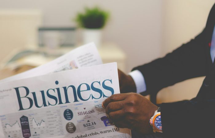 Professional reading a business newspaper with market data and financial charts