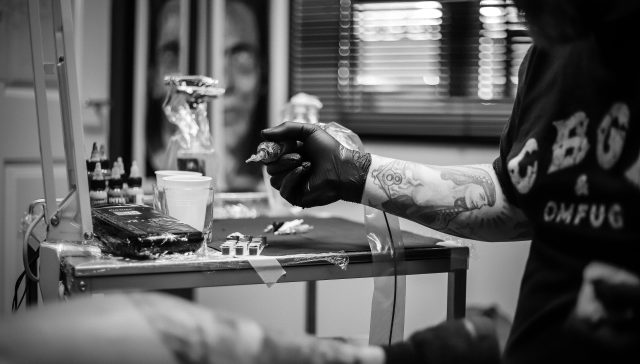 Tattoo artist holding a tattoo machine in a studio setting