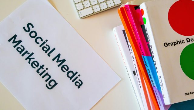 A desk showing materials on social media marketing and graphic design representing marketing leaders exploring the O-1A visa.