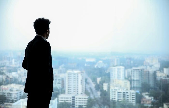 A corporate executive in a suit looking out over a city skyline, representing business leaders exploring O-1A, EB-1A, and EB-2 NIW immigration pathways.