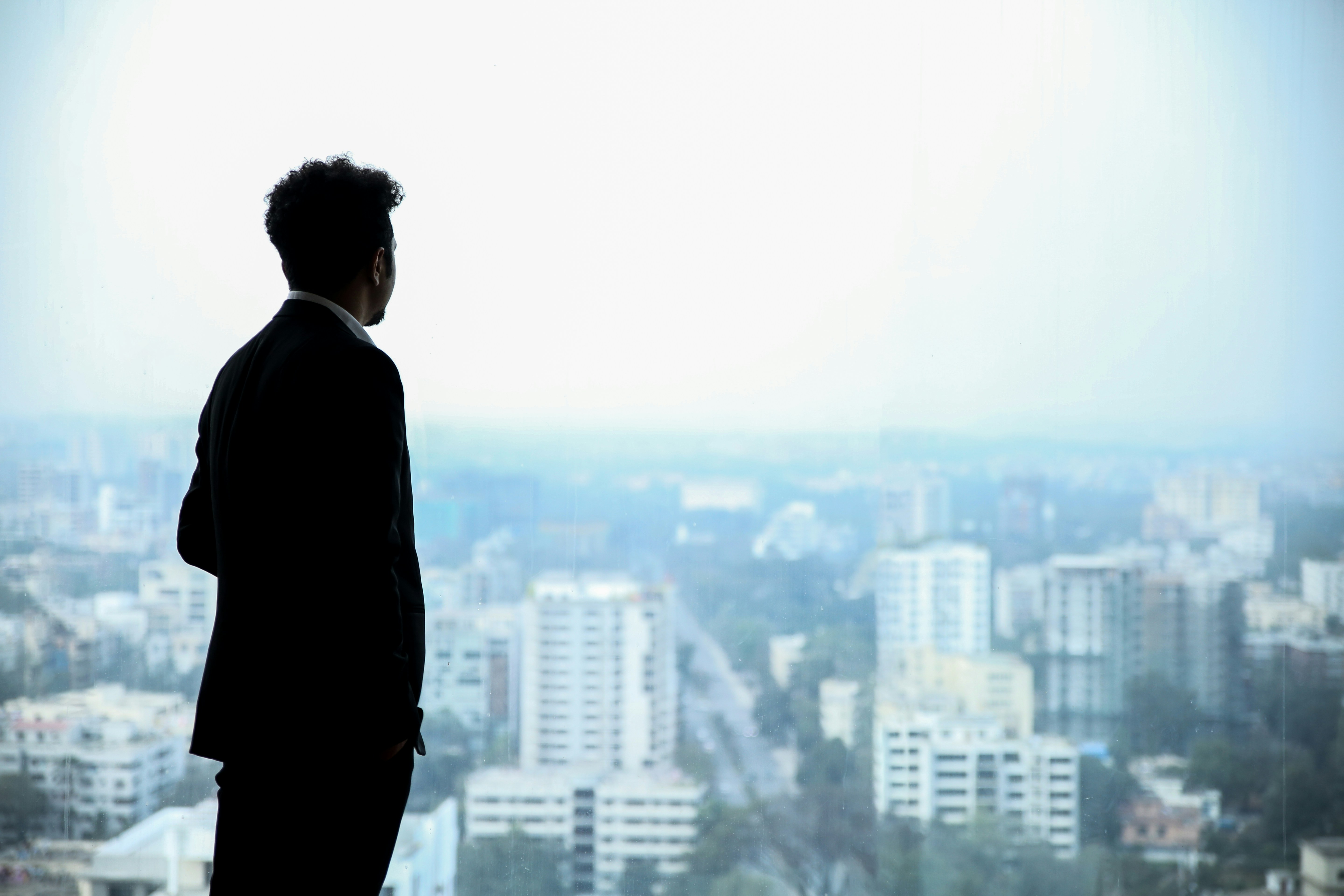 A corporate executive in a suit looking out over a city skyline, representing business leaders exploring O-1A, EB-1A, and EB-2 NIW immigration pathways.